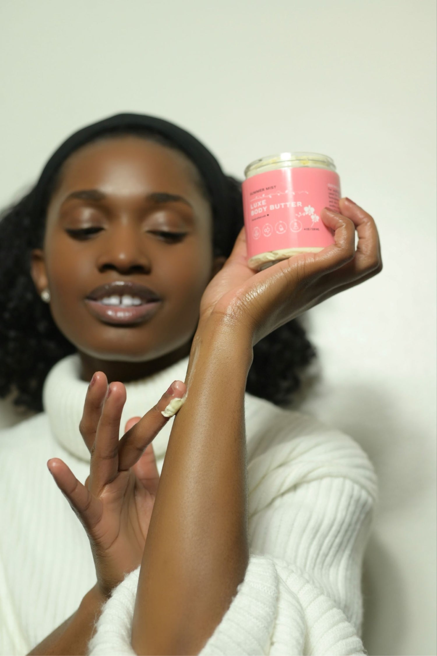 Black female model applying zen & bloom body butter to hand
